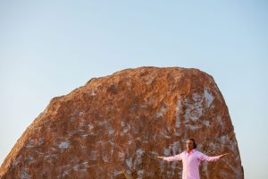 Bild eines segnenden Mannes vor eine roten Felskuppe
