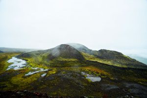 grüne Berglandschaft im schwarzen Vulkangebiet