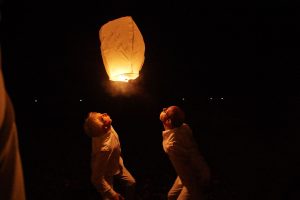 Nächtliches Foto zweier Männer, die einen Papierballon von unten anpusten