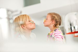 Foto von Mutter und Tochter, die je einen bunten Strohhalm zwischen ihrem Mund und Nase halten