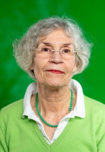 Portrait von einer grauhaarigen Frau vor grünem Hintergrund