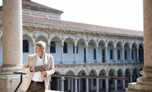 Portrait von einem Forschungsprofessor im Wandelgang in Mailand, sein iPad lesend