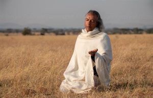 In Hingabe sitzender Mann segnet die Serengeti
