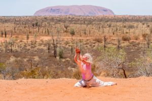 Tänzerin tanzt hingebungsvoll im Sand vor dem Uluru