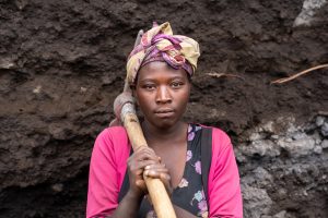 Portrait einer afrikanischen Schönheit und geschultertem Schlaghammer im Steinbruch