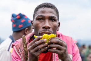 Portrait eines hungrigen afrikanischen jungen Erwachsenen, der eine Frucht isst